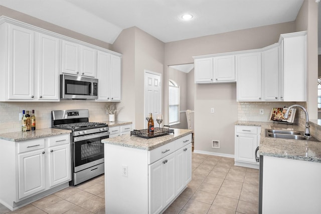 kitchen with light tile patterned floors, appliances with stainless steel finishes, a sink, and white cabinetry