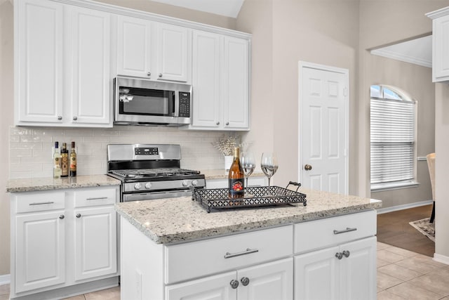 kitchen featuring tasteful backsplash, white cabinetry, stainless steel appliances, and light stone counters