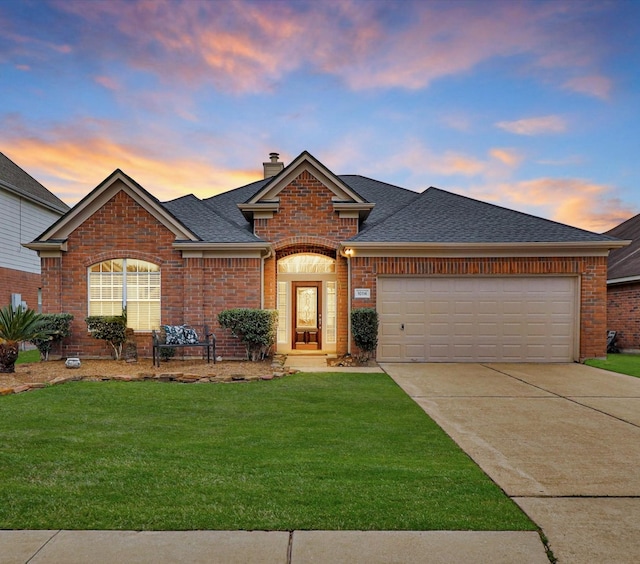 view of front of home with concrete driveway, a chimney, a lawn, and brick siding