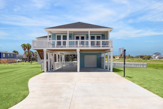 coastal home featuring covered porch, roof with shingles, stairway, a carport, and a front yard