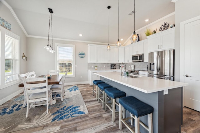 kitchen featuring stainless steel appliances, light countertops, white cabinetry, and a kitchen island with sink