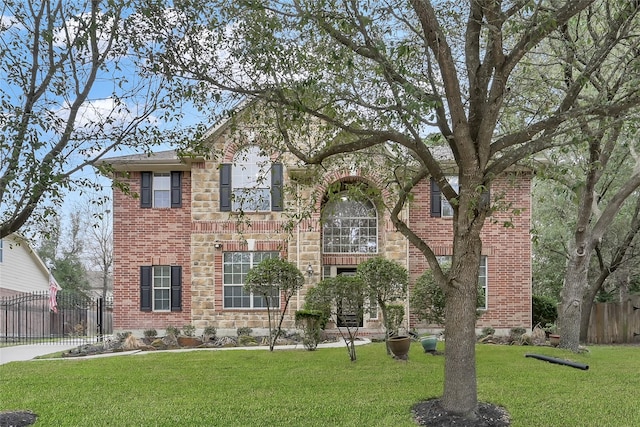 traditional home featuring brick siding, a front lawn, fence, and stone siding