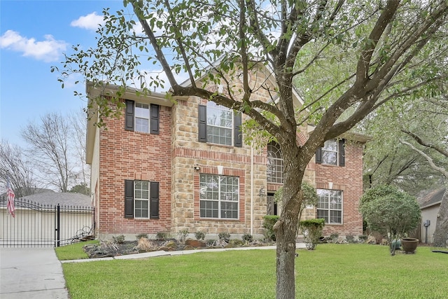 traditional home with brick siding, fence, stone siding, a gate, and a front lawn