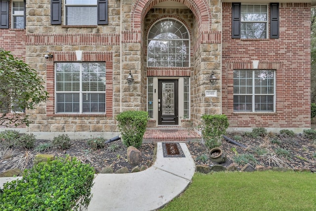 entrance to property featuring stone siding and brick siding