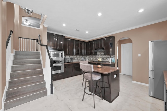 kitchen featuring stainless steel appliances, arched walkways, marble finish floor, and a kitchen island