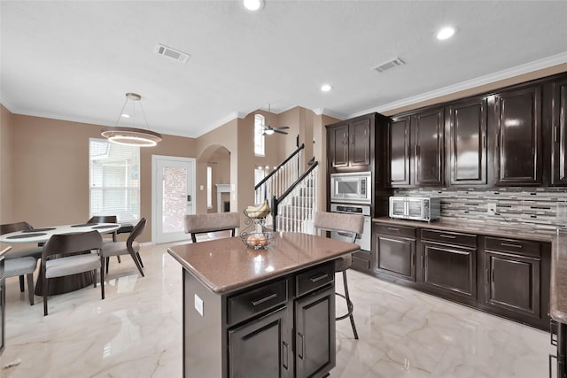 kitchen featuring visible vents, marble finish floor, appliances with stainless steel finishes, a center island, and pendant lighting