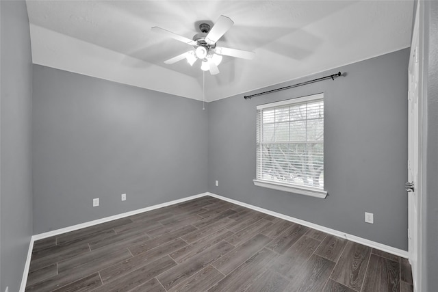 spare room featuring dark wood-style floors, baseboards, and a ceiling fan