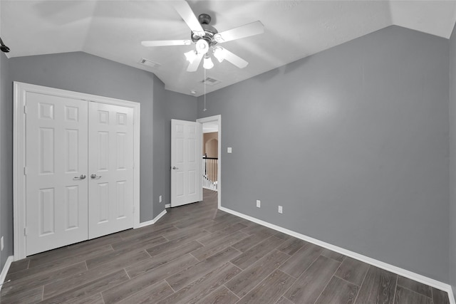 unfurnished bedroom featuring wood tiled floor, a closet, visible vents, and vaulted ceiling