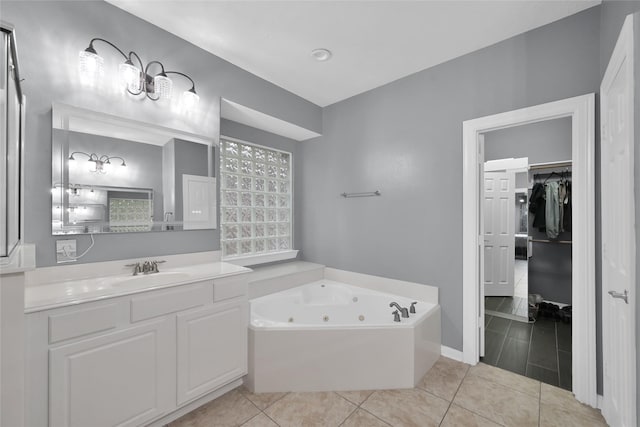 bathroom featuring tile patterned flooring, a walk in closet, vanity, and a whirlpool tub