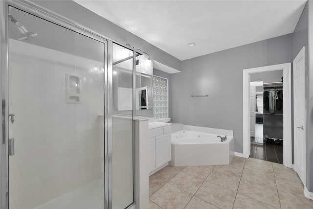 full bath featuring a walk in closet, a stall shower, vanity, tile patterned flooring, and a bath