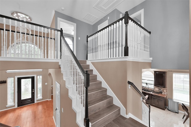 staircase featuring arched walkways, wood finished floors, baseboards, a chandelier, and a high ceiling