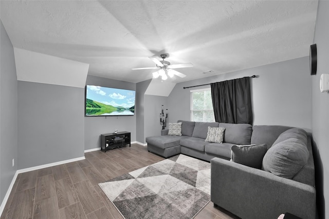 living room with ceiling fan, a textured ceiling, wood finished floors, baseboards, and vaulted ceiling