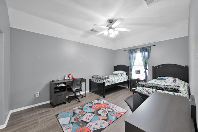 bedroom with visible vents, baseboards, ceiling fan, and wood finished floors