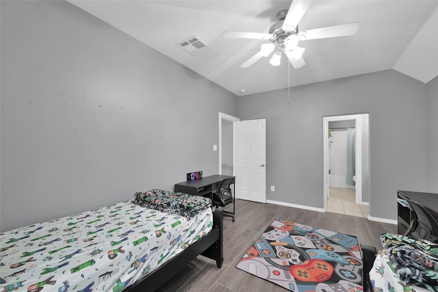 bedroom featuring ceiling fan, visible vents, vaulted ceiling, wood finished floors, and baseboards