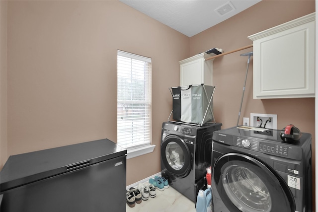 clothes washing area with cabinet space, baseboards, visible vents, and washer and clothes dryer