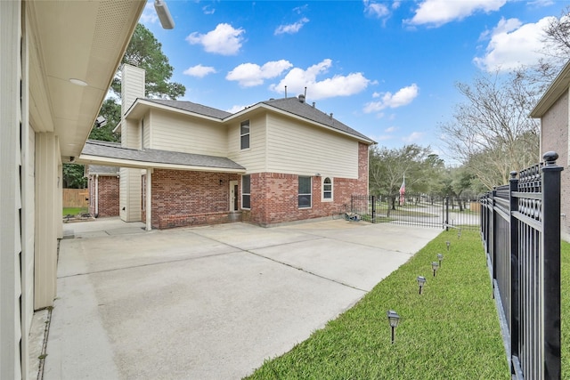 view of property exterior featuring fence, a patio, driveway, and brick siding