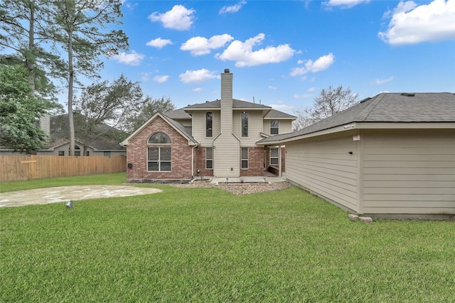 back of house with fence, a patio, a chimney, brick siding, and a lawn