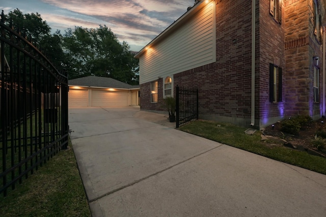 view of property exterior with brick siding, an outdoor structure, fence, and a detached garage