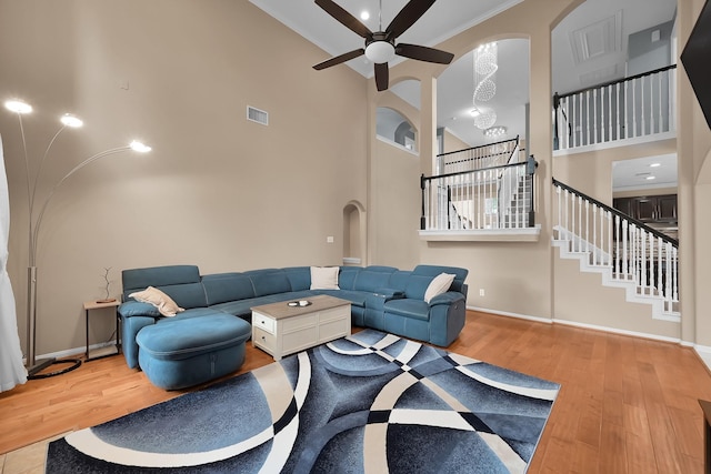 living area with ceiling fan, stairs, wood finished floors, a towering ceiling, and visible vents