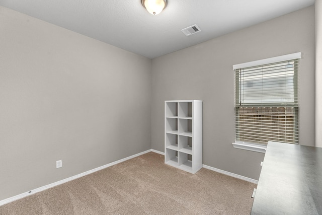 interior space featuring baseboards, visible vents, and light colored carpet