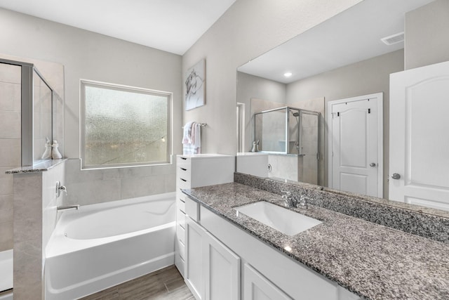 bathroom with a garden tub, visible vents, a stall shower, vanity, and wood finished floors