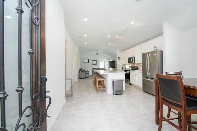 kitchen with appliances with stainless steel finishes, a breakfast bar, a center island with sink, and white cabinetry