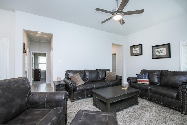 living area with light tile patterned floors, ceiling fan, and attic access