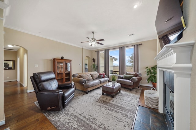 living area featuring baseboards, a fireplace, arched walkways, and crown molding