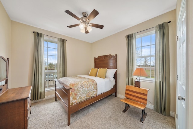 bedroom featuring baseboards, multiple windows, and light colored carpet