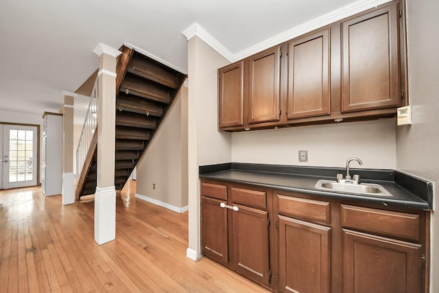 4900 Sandalwood Cir, Baytown, TX 77521 - kitchen with crown molding, dark countertops, light wood-style floors, a sink, and baseboards