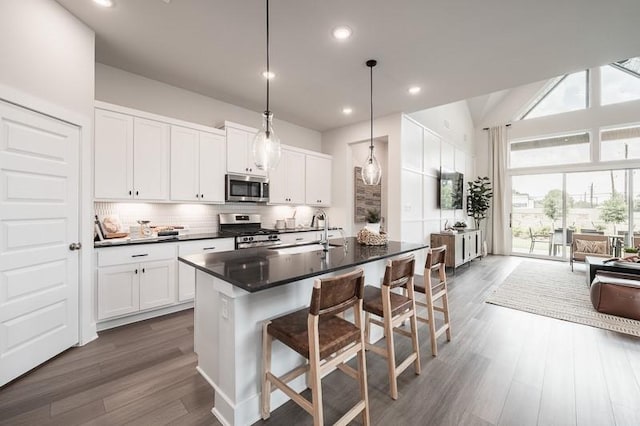 kitchen with appliances with stainless steel finishes, dark countertops, a sink, and a breakfast bar