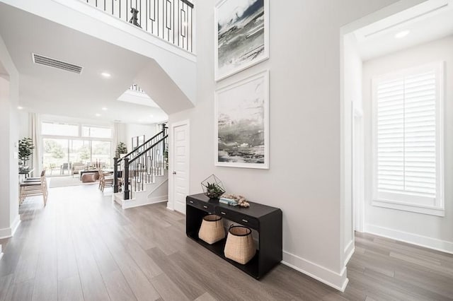 hall featuring visible vents, stairs, baseboards, and wood finished floors