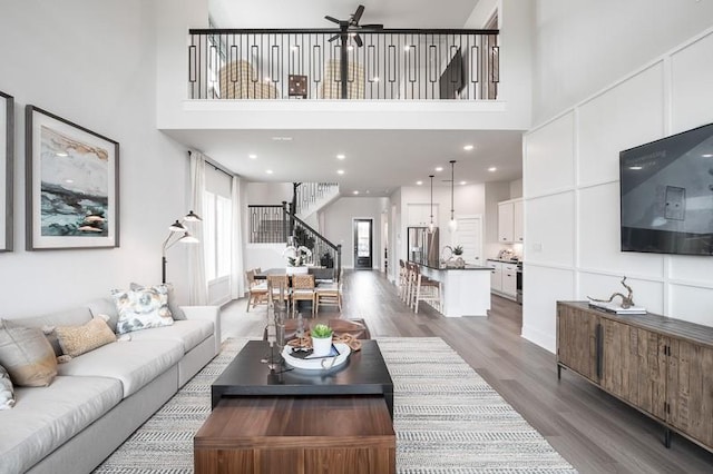 living area with stairs, dark wood finished floors, a towering ceiling, and recessed lighting