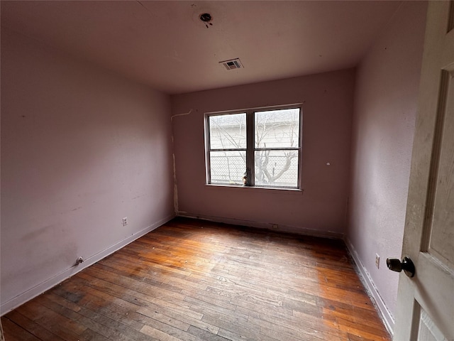 spare room with baseboards, visible vents, and wood finished floors