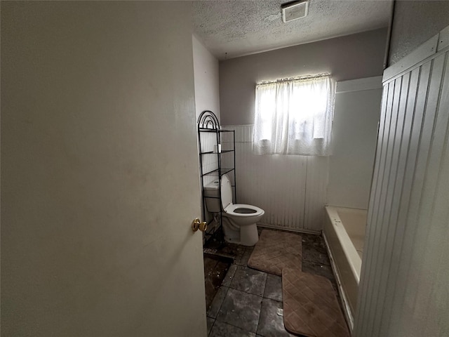 full bathroom with a bathtub, visible vents, a textured ceiling, and toilet