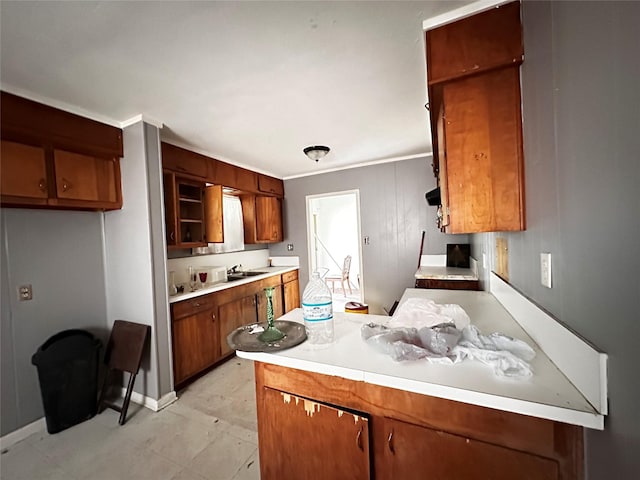 kitchen with light countertops, a sink, and brown cabinets