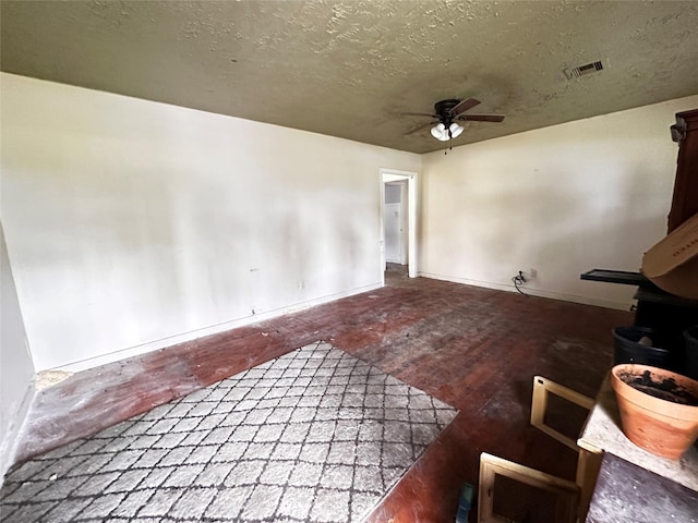 unfurnished living room featuring baseboards, a textured ceiling, visible vents, and a ceiling fan