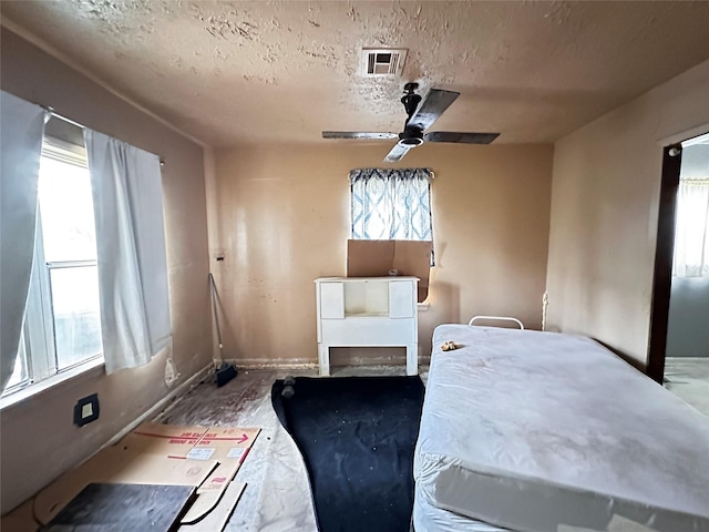 bedroom featuring a textured ceiling, ceiling fan, visible vents, and baseboards