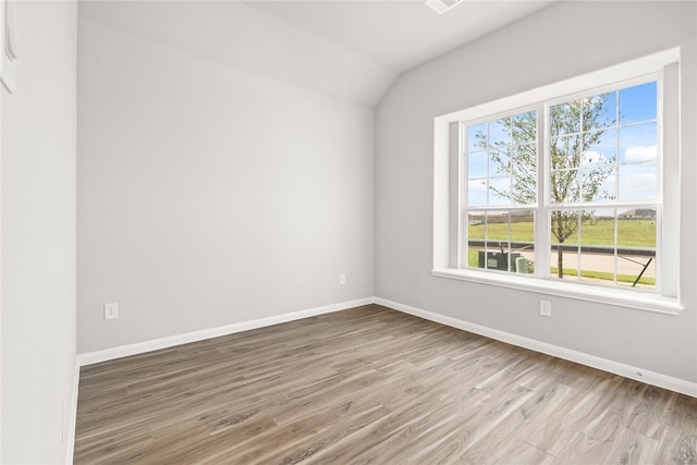 spare room featuring vaulted ceiling, wood finished floors, and baseboards