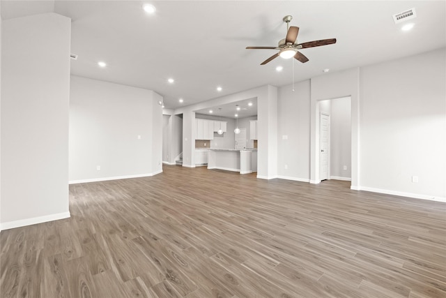 unfurnished living room with recessed lighting, wood finished floors, visible vents, baseboards, and a ceiling fan