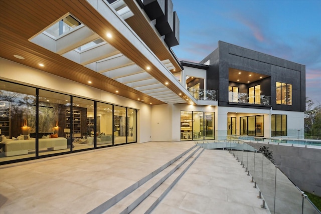 back of property at dusk featuring a patio area and stucco siding