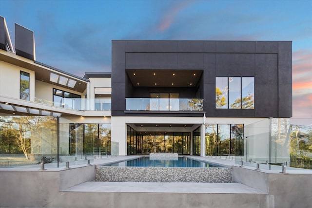 back of house featuring an outdoor pool and stucco siding