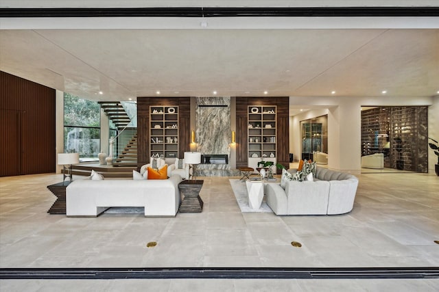 living room featuring built in features, recessed lighting, wood walls, and stairway