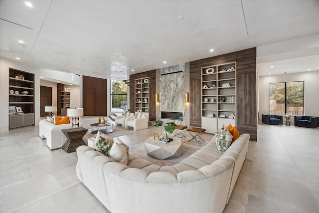 living area featuring a healthy amount of sunlight, built in shelves, a high end fireplace, and recessed lighting