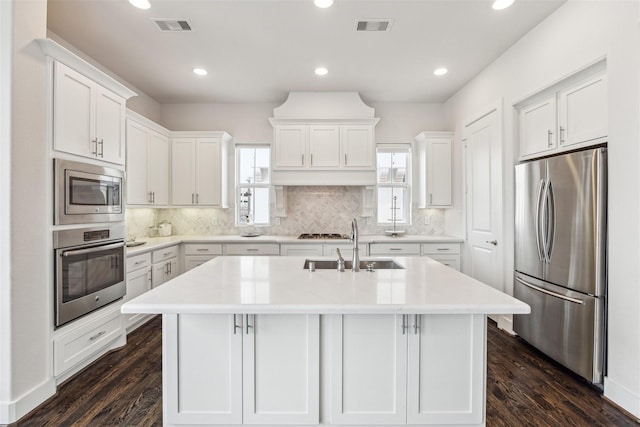 kitchen featuring a center island with sink, stainless steel appliances, light countertops, visible vents, and white cabinets