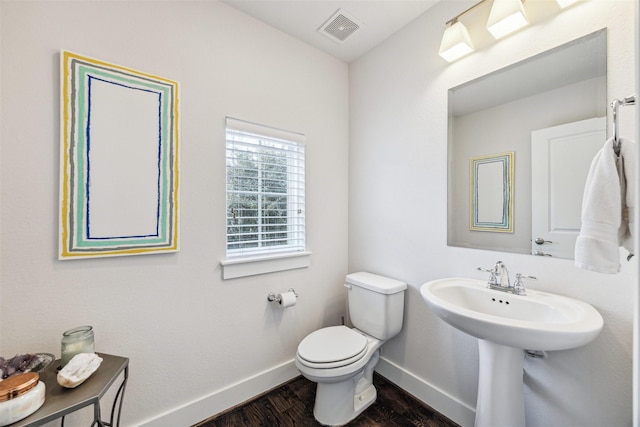 bathroom featuring baseboards, visible vents, toilet, wood finished floors, and a sink