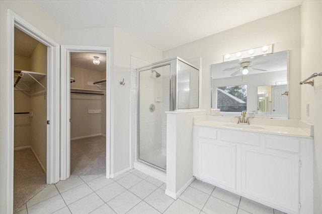 bathroom with a shower stall, a walk in closet, tile patterned flooring, and vanity