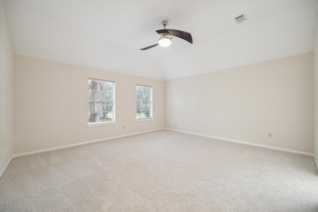 empty room featuring visible vents, vaulted ceiling, light carpet, and baseboards