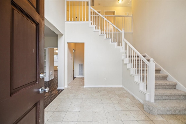 entryway with a towering ceiling, stairs, and baseboards