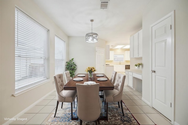 dining space featuring baseboards, visible vents, and light tile patterned flooring